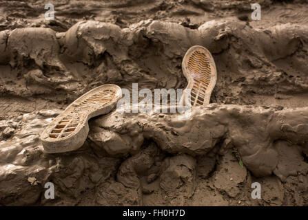 Zwei Schuhsohlen verloren in einem schlammigen Feld Stockfoto