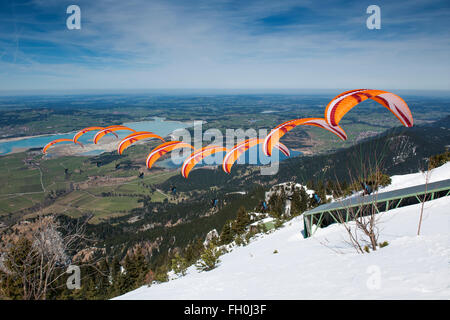 Füssen, Deutschland - 9. April 2015: orange Gleitschirm Start vom Tegelberg über die Foggenlake Stockfoto