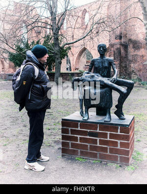 Senior woman Blick auf Bronze-Skulptur "Pieta" von Jürgen Pansby auf Ruine des Berliner Franziskaner Kloster, Franziskaner-Klosterkirche. Stockfoto
