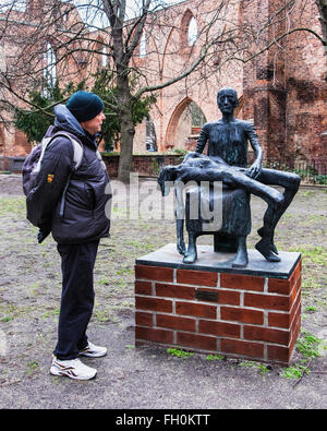 Senior woman Blick auf Bronze-Skulptur "Pieta" von Jürgen Pansby auf Ruine des Berliner Franziskaner Kloster, Franziskaner-Klosterkirche. Stockfoto