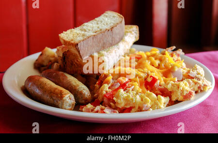 Leckeres Rührei mit Käse, Wurst, Kartoffeln und Toast zum Frühstück Stockfoto