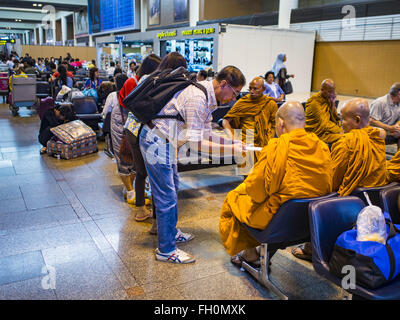 Bangkok, Thailand. 23. Februar 2016. Ein Mann spricht mit buddhistischen Mönchen in der Lobby Abfahrten am Don Mueang International Airport. NOK Air, teilweise im Besitz von Thai Airways International und einer der größten und erfolgreichsten Billigfluglinien in Thailand, 20 Flüge Dienstag wegen einem Mangel an Piloten gestrichen und kündigte an, dass andere Flüge abgesagt oder über das Wochenende gesperrt werden würde. Die Stornierungen kam nach ein wilden Streik von mehreren Piloten Sonntagabend Flüge annullierte und Reisende mehr als tausend gestrandete. Der pilot Mangel bei Nok kommt zu einem Zeitpunkt wenn der Th Stockfoto