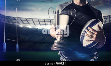 Zusammengesetztes Bild des Mittelteils des erfolgreicher Rugbyspieler holding, Pokal und ball Stockfoto