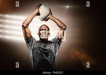 Zusammengesetztes Bild des ermittelten Sportler wirft Rugby-ball Stockfoto