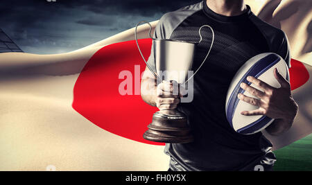 Zusammengesetztes Bild des Mittelteils des erfolgreicher Rugbyspieler holding, Pokal und ball Stockfoto