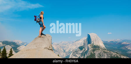 Wanderer auf einem Felsen stehend, mit Blick auf Half Dome, Blick vom Glacier Point, Yosemite-Nationalpark, Kalifornien, USA Stockfoto