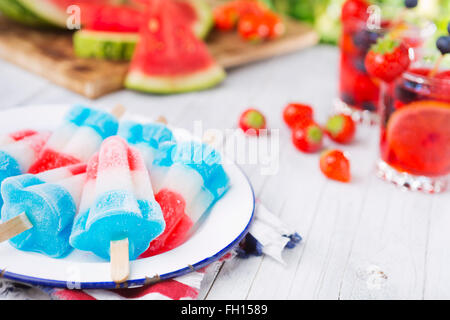 Hausgemachte rot-weiß-blauen Eis am Stiel auf einen Tisch im Freien mit erfrischenden Limonade im Hintergrund. Stockfoto