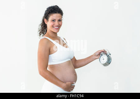 Lächelnd schwangere Frau Holding Wecker Stockfoto