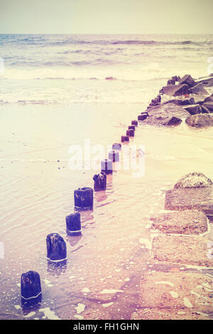 Retro-alte Film stilisierte Foto von einem Wellenbrecher am Strand. Stockfoto