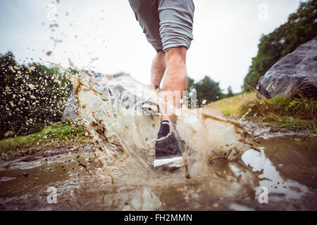 Mann durch Schlammpfützen Joggen Stockfoto