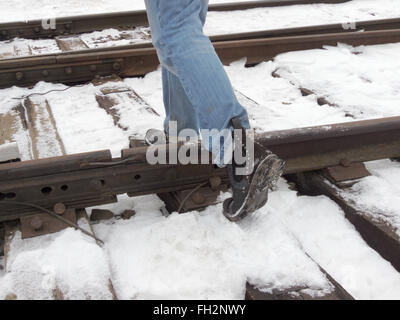 Schritt über die Schienen, zu Fuß auf den Schwellen im Winter in die Stiefel Stockfoto