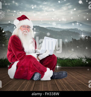 Zusammengesetztes Bild von Santa sitzt und einen laptop Stockfoto