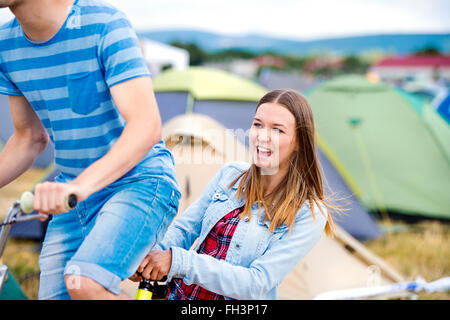 Teenager-Paar Reiten Fahrrad zusammen im Sommer-Musikfestival Stockfoto