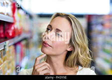 Nachdenkliche Frau betrachten Regale Stockfoto