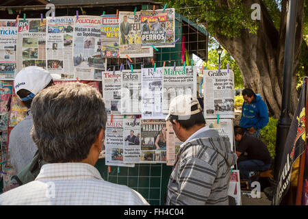 Oaxaca, Mexiko - Leute lesen die Schlagzeilen der Zeitungen an einem Kiosk in El Llano Park. Stockfoto