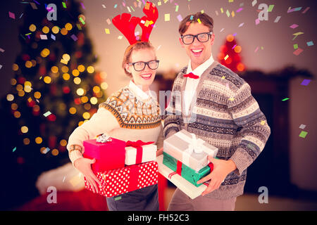 Zusammengesetztes Bild des lächelnden Frau trägt rote Rentierhorn und hält Geschenke mit Mann Stockfoto