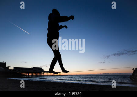 Ein Slackline-Spaziergänger am Strand von Aberystwyth bei Sonnenuntergang Stockfoto