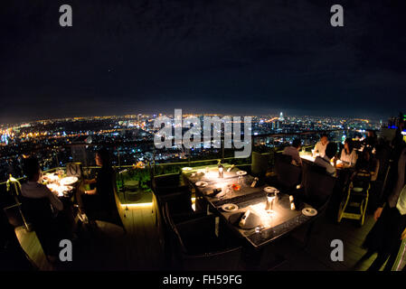 BANGKOK, Thailand – die glitzernde Skyline von Bangkok erstreckt sich unterhalb des Hotels vom Dachrestaurant Vertigo auf dem Dach des Banyan Tree Hotel aus. Wolkenkratzer und Hochhäuser beleuchten die weitläufige thailändische Hauptstadt mit unzähligen Lichtern und schaffen ein atemberaubendes Stadtpanorama. Stockfoto