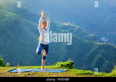 Frau tut Yoga Asana Baumpose im freien Stockfoto