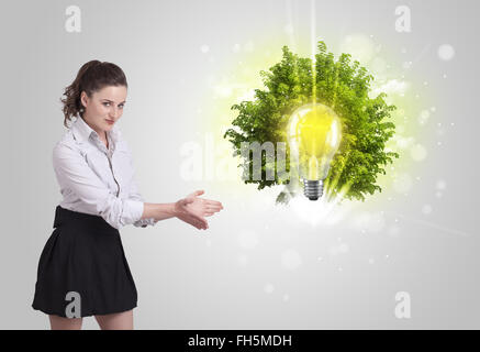 Junges Mädchen präsentieren Idee Glühbirne mit grüner Baum Stockfoto