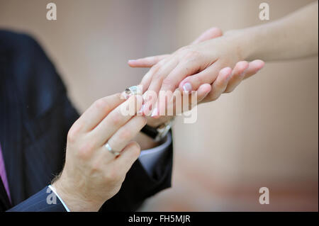 des Bräutigams Hand setzen einen Ehering am Finger der Braut Stockfoto