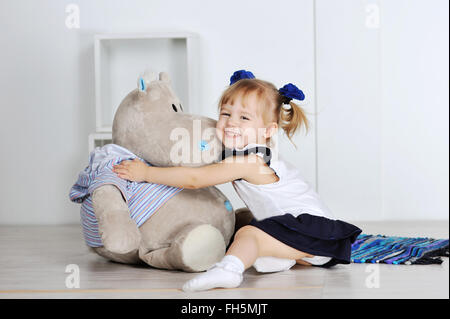 Kleines Mädchen umarmt ein Teddy Nilpferd im studio Stockfoto