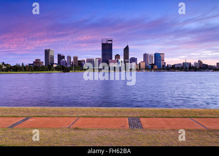 Panoramablick von Wolkenkratzern in Perth, Western Australia, über Swan River bei Sonnenaufgang. Wanderweg im Hintergrund. Stockfoto