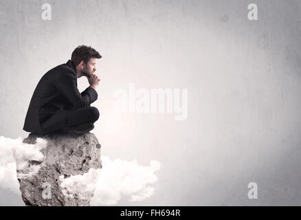 Büroangestellter sitzt auf einem Felsen Stockfoto