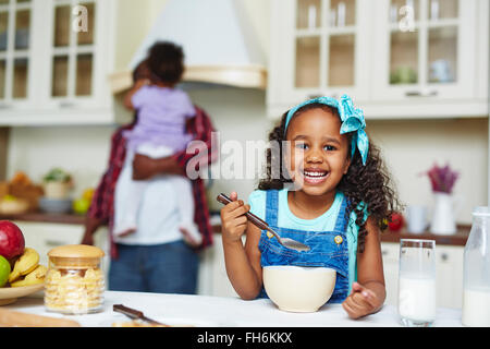 Fröhliches afroamerikanische Mädchen Essen morgens cornflakes Stockfoto