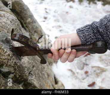 Hand des tapferen Ritters versucht, das magische Schwert Excalibur in den Stein zu entfernen Stockfoto