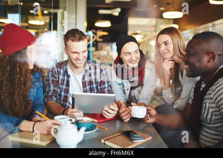 Freundlichen Jungs und Mädels mit Touchpad mit schöne Zeit im café Stockfoto