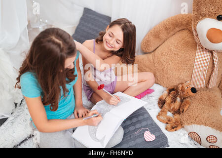 Draufsicht der zwei fröhliche charmante Schwestern sitzen und Färbung im Spielzimmer zu Hause Stockfoto