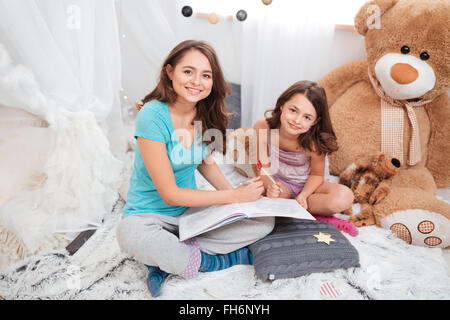 Zwei süße Lächeln Schwestern sitzen und zeichnen zusammen im Kinderzimmer Stockfoto