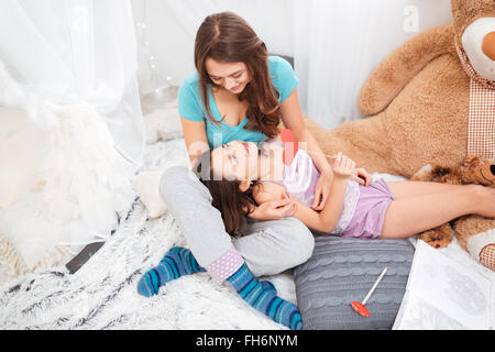 Zwei glückliche niedlich Schwestern liegen und im Kinderzimmer zu Hause sprechen Stockfoto