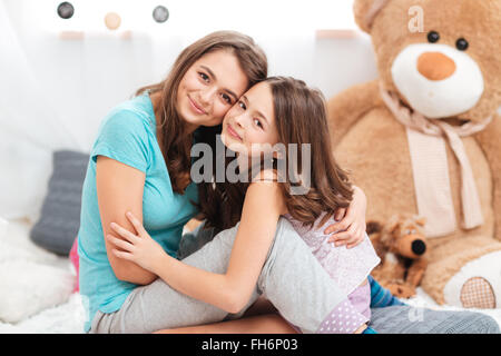 Zwei süße schöne Schwestern sitzen und umarmt im Kinderzimmer Stockfoto