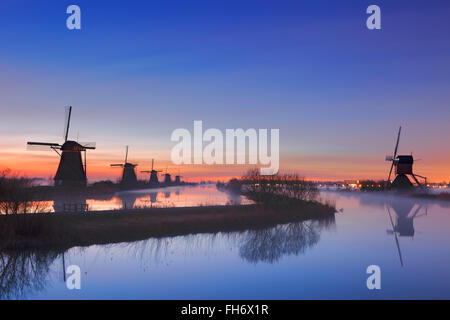 Traditionelle holländische Windmühlen mit Bodennebel kurz vor Sonnenaufgang. Die berühmte Kinderdijk fotografierte. Stockfoto