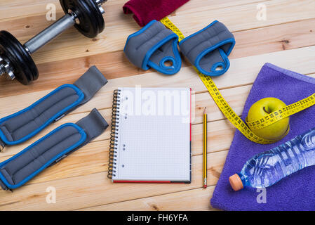 Sportgeräte. Hanteln, Fussblei, Handgelenk Gewichte, Handtuch, Apple, Band-Maß, Flasche Wasser und Notebook Stockfoto