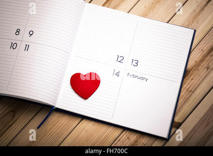 Rotes Herz aus Holz und Kalender auf Holzbrettern. 14. Februar. Valentinstag-Konzept Stockfoto