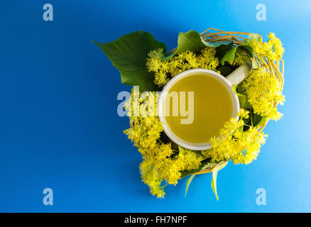 Tasse Tee in geflochtenen Weidenkorb gefüllt mit Lindenblüten Stockfoto