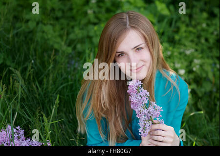 schöne Frau mit einem Zweig von Flieder im Frühlingsgarten Stockfoto