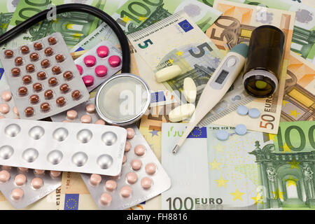 medizinische Pillen, Stethoskop und Thermometer in Euro Geld Hintergrund als Symbol der Kosten im Gesundheitswesen Stockfoto