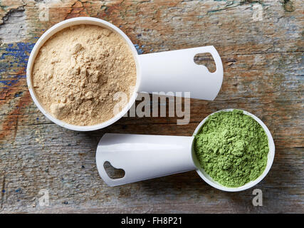 Messung der Kugeln von Maca und Gerste oder Weizen Grass Pulvern auf Holztisch Stockfoto