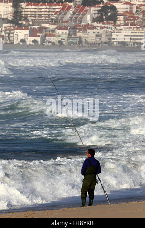 Mann Meeresangeln vom Sandstrand entfernt, Vila Praia de Ancora in Hintergrund, Provinz Minho, Nordportugal Stockfoto