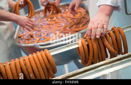 München, Deutschland. 24. Februar 2016. Metzger aufhängen Würstchen am Stand des Verbandes der deutschen Metzger (Deutscher Fleischer-Verband) während die Internationale Handwerksmesse Handwerk Messe in München, Deutschland, 24. Februar 2016. Mehr als 1000 Aussteller aus 60 Geschäfte werden auf der Messe, d.h. bis zum 01.03.2016. Foto: SVEN HOPPE/DPA/Alamy Live-Nachrichten Stockfoto