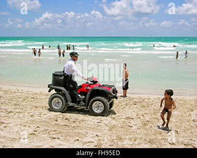 Miami, Florida, USA - 28. Mai 2007: Ein Polizist auf Streife, sein Quad-Fahrrad rot, läuft am Strand zieht die Blicke von einigen Stockfoto