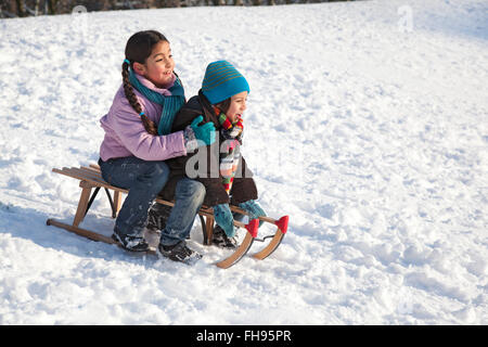 Zwei Kinder auf einem Schlitten Spaß im Schnee Stockfoto