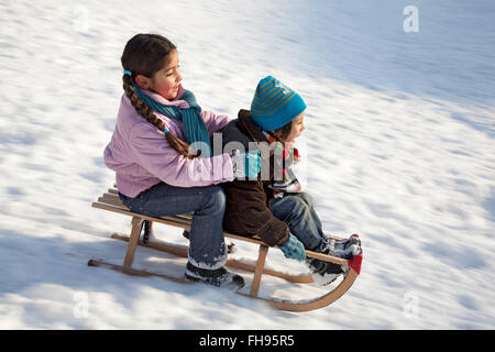 Zwei Kinder auf einem Schlitten Spaß im Schnee Stockfoto