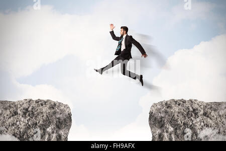 Funny Business Mann springt über Felsen mit Lücke Stockfoto