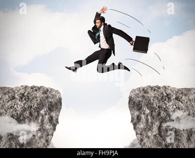 Funny Business Mann springt über Felsen mit Lücke Stockfoto
