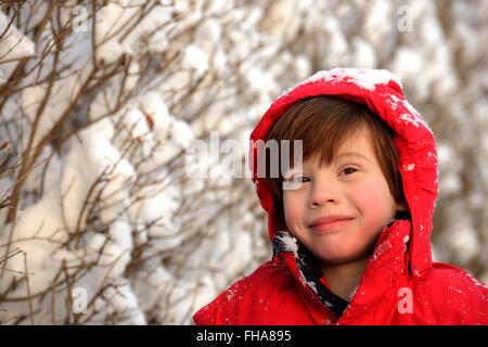 Kleiner Junge trägt einen roten Mantel im Schnee Stockfoto